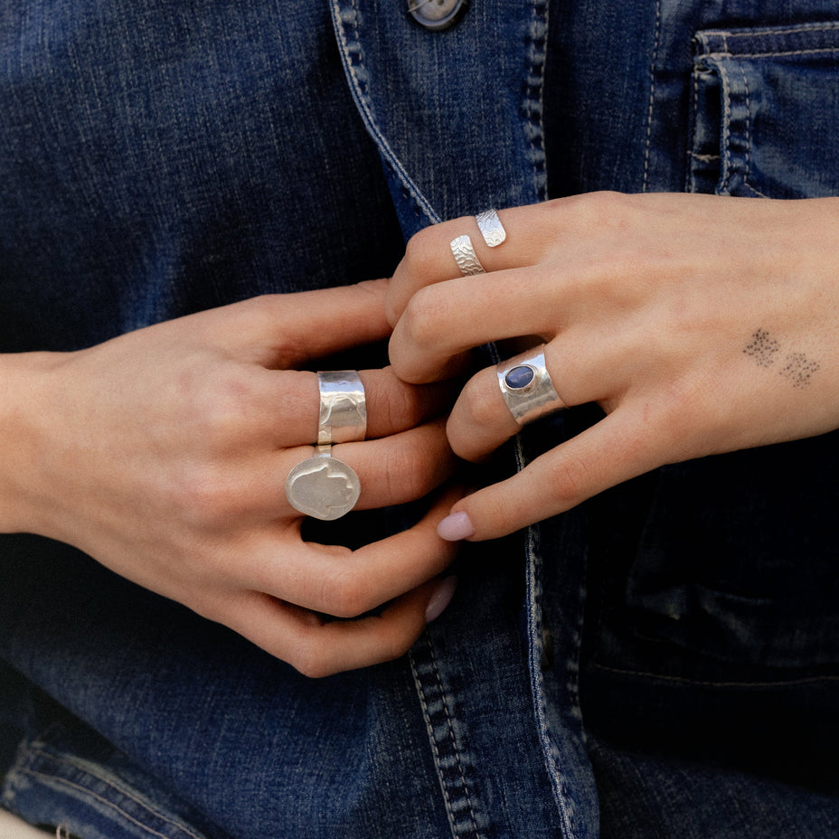 Close-up of hands wearing silver rings with a denim background